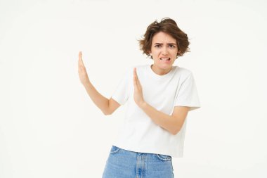 Birinden kaçınan kadın portresi, el hareketlerini engeller ve kötü bir şeyi reddeder, beyaz arka planda durur..