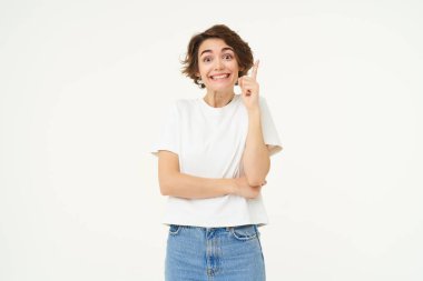 Heyecanlı kızın bir fikri var, bir plan öneriyor, işaret ediyor, parmağını kaldırıyor ve gülümsüyor, çözümü var, beyaz arka planda duruyor..