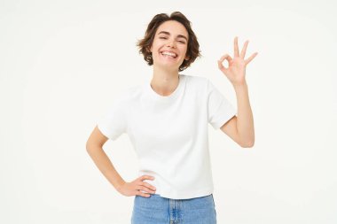 Hiç sorun değil. Kendine güvenen genç bir kadının portresi, tamam, sıfır jest, beyaz stüdyonun arka planında duruyor..