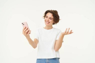 Arkadaşlarıyla görüntülü kadın sohbetleri, bir şeyler göstermek, göstermek, akıllı telefondan online bir toplantı, beyaz arka planda durmak.