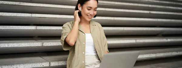 노동자 이시아 소녀는 노트북을 가지고 길거리에 있습니다 컴퓨터로 일하는 헤드폰으로 — 스톡 사진