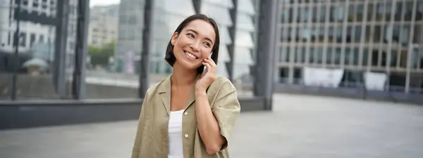 Uśmiechnięta Młoda Koreanka Rozmawiająca Przez Telefon Komórkowy Spacerująca Mieście Szczęśliwa — Zdjęcie stockowe