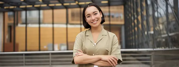 stock image Portrait of young asian woman standing with confidence, cross arms on chest and smiling, posing outdoors on street.