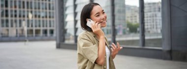 Hücresel bağlantı. Genç Asyalı kadın bir telefon görüşmesi yapar, cep telefonuyla konuşur ve sokakta yürür..