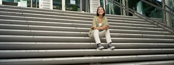 이시아 소녀의 모습은 계단에 스마트폰 사용하고 휴대폰 화면을 보면서 메시지를 — 스톡 사진