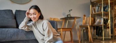 Güzel Asyalı bir kadının dikey çekimi, evde oturan ve uzaktan çalışan bir öğrenci, dizüstü bilgisayarla çalışıyor..