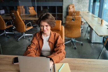 Ofiste çalışan bir kadının portresi, daktilo, dizüstü bilgisayarda kodlama, günlük kıyafetlerle oturmak..