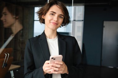 Şirket kadını resmi, iş şirketinde satış elemanı, siyah takım elbiseli, akıllı telefon tutan, müşteriyi arayan..