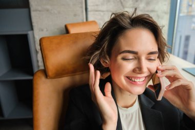 Şirkette çalışan, telefonlara cevap veren, gülen ve gülümseyen başarılı bir kadının portresi..