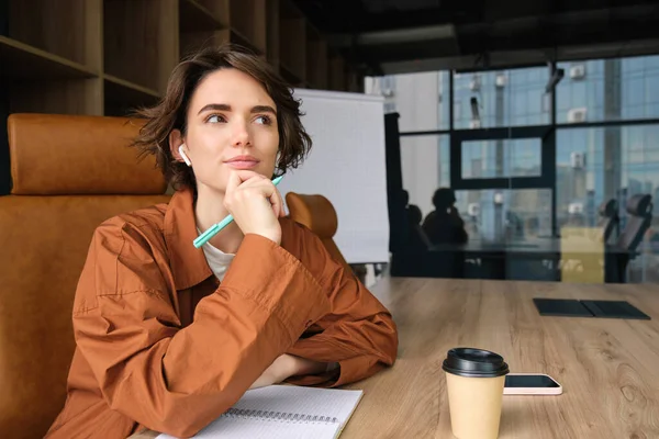 Portrait of female employee working in office, businesswoman in casual clothes writing, making notes in documents, sitting in conference room, having a meeting.