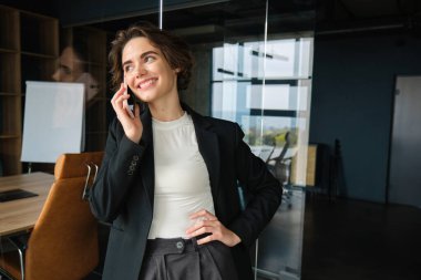 Kendine güvenen bir iş kadınının telefon görüşmesine cevap vermesi, telefonda konuşması, gülümsemesi, ofiste durması ya da ortak çalışması..