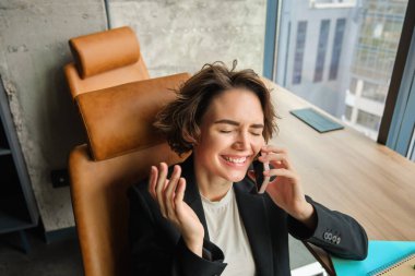Konferans odasında bir kadın resmi, iş kadını pencerenin önünde çalışıyor, telefona cevap veriyor ve gülüyor..