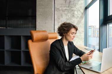 Şirkette çalışan genç bir kadın, ofisinde dava üzerinde çalışıyor, siyah takım elbiseli bir bilgisayarın önünde oturuyor..