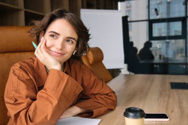 Ofiste çalışan kadın çalışanın portresi, günlük kıyafetlerle yazı yazan iş kadını, belgelerle notlar alan, konferans odasında oturan, toplantı yapan.