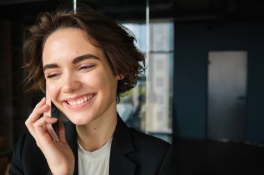 Başarılı bir iş kadınının portresi telefon görüşmesi yapıyor, ofiste duruyor ve müşteriyle konuşuyor..