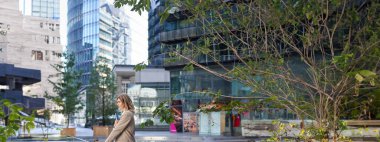 Sokakta duran bej takım elbiseli kurumsal kadının dikey fotoğrafı. İşten önce sabah kahvesini yudumluyor..