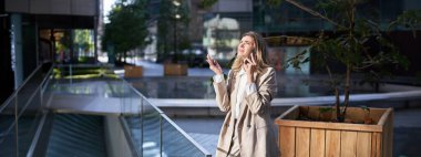 Hüsrana uğramış kurumsal kadın sokakta dikiliyor ve zor bir telefon görüşmesi yapıyor, telefon konuşmasında kötü haberler duyuyor..