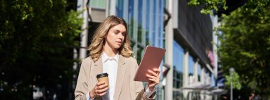 Başarılı bir iş kadını işe giderken iş projesini kontrol ediyor, dijital tabletle sokakta duruyor, kahve servisi yapıyor..