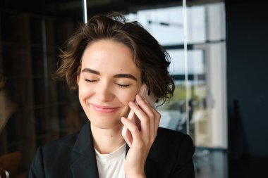 Kendine güvenen bir iş kadınının telefon görüşmesine cevap vermesi, telefonda konuşması, gülümsemesi, ofiste durması ya da ortak çalışması..