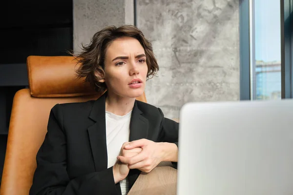 Portrait of woman with concerned face, hearing out problems during conference or business meeting, looking at laptop with worried expression.