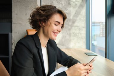 Şirkette çalışan genç bir kadın, ofisinde dava üzerinde çalışıyor, siyah takım elbiseli bir bilgisayarın önünde oturuyor..