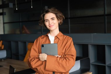 Satış işinde çalışan bir kadının portresi, elinde tabletle pazarlama müdürü, ofiste dikiliyor, günlük kıyafetler giyiyor..