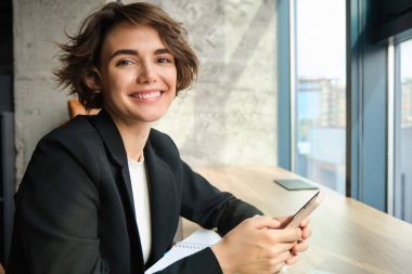 Akıllı telefonlu çalışkan bir kadının portresi, ofisinde oturan, iş kadını....