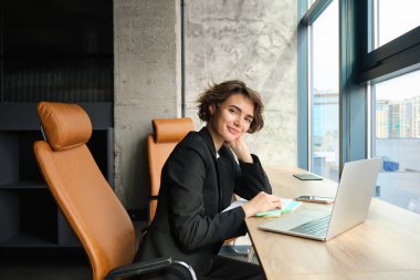 Dizüstü bilgisayarda çalışan satış elemanı portresi, ofiste oturmak ve bir müşteriyle görüşmeye hazırlanmak..