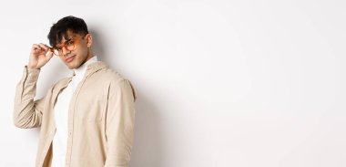 Yakışıklı adam seni selamlıyor, göz teması kuruyor, küstah sırıtıyor, beyaz arka planda duruyor..