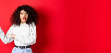 Tişörtlü, beyaz, heyecanlı bir kadın, pankartı kontrol ediyor, boş yeri işaret ediyor, reklam gösteriyor, kırmızı arka plan..