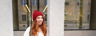 Stylish urban girl using mobile phone app, standing in city, waiting for taxi, looking at smartphone application, texting message.