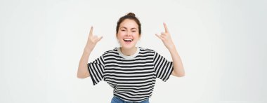 Çekici, kaygısız dans eden, heavy metal gösteren, jest üzerine rock yapan, beyaz arka planda duran kadın portresi..