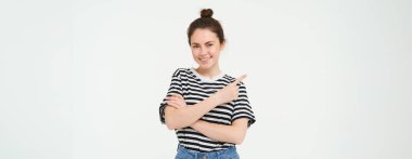 Gülümseyen, güzel, esmer bir kadının portresi, solu işaret eden, reklam veren, beyaz stüdyo arka planı.