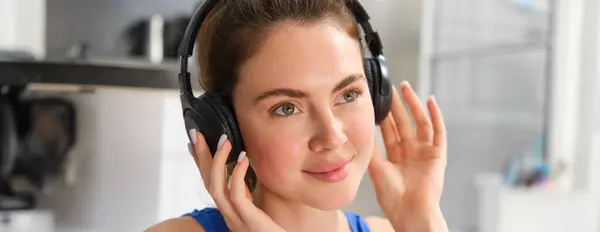 Face of beautiful woman in wireless headphones, enjoys sound, listens to music in wireless headphones.