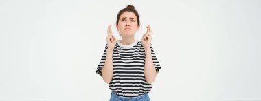 Büyük umutlar. Genç bir kadın dua ediyor, dilek tutuyor, bir şeyler bekliyor, beyaz arka planda duruyor..