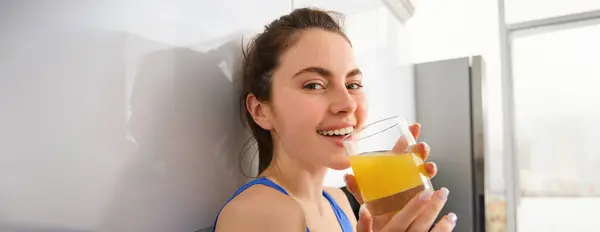 stock image Portrait of smiling brunette sportswoman, drinking fresh juice, detox drink, enjoys freshly squeezed beverage after workout training session.