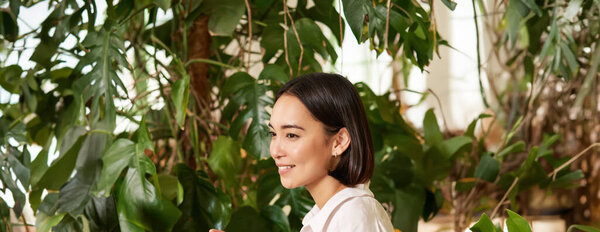 Вертикальный снимок красивой женщины сидит в кафе с ноутбуком, работает или учится онлайн в коворкинг-пространстве, улыбаясь расслабленной.