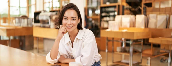 stock image Portrait of confident asian woman, sitting in cafe, smartphone and coffee on table. Businesswoman smiling with confidence. Copy space