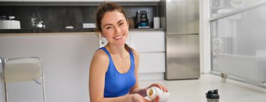 Güçlü ve sağlıklı sporcunun evde spor yaptığı, haplar, vitaminler ya da diyet takviyeleri aldığı spor, sağlık ve ilaç konsepti