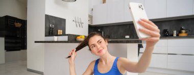 Güzel esmer sporcunun portresi, akıllı telefonda selfie çekmek, cep telefonuyla fitness minderinde poz vermek, spor egzersizlerini kaydetmek, antrenman yapmak..