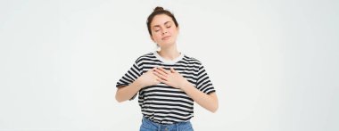 Tutkulu kız kalbinin üstünde el ele tutuşur ve gülümser, beyaz arka planda durur..