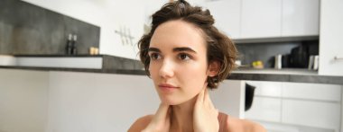 Aktif giyimde fitness kızı, evde yoga yapıyor, esneme ve egzersiz yapıyor, boynuna zevk veren, rahat yüz ifadesiyle masaj yapıyor. Spor ve refah kavramı