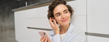 Akıllı telefonlu mutlu bir kızın kapalı çekimleri, evde oturup cep telefonu kullanması, uygulamadan video izlemesi, uygulamadan arkadaşlarıyla sohbet etmesi..