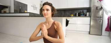 Gülümseyen kız atlet, spor kadın aktif giyimde yoga yapıyor, nilüfer pozisyonunda yoga minderinde oturuyor, meditasyon yapıyor, farkındalık egzersizleri yapıyor..