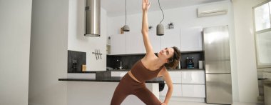Sağlıklı ve zinde kalın. Spor kıyafetli güzel bir Asyalı kadın evde dinlenirken yoga yapıyor..