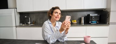 Akıllı telefonu tutan, cep telefonu uygulamasından ne sipariş vereceğine karar veren bir kadının portresi.