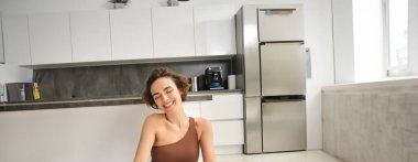 Gülümseyen esmer formda bir kadın, meditasyon yapan genç bir sporcu, evde yoga yapan, farkındalık uygulayan....