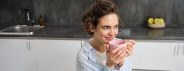 Gülümseyen genç bir kadının portresi, mutfakta kahve içen, sabah sihri ile çay içen, şefkatle bakan.