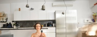 Dikey çekimde, genç bir kadın meditasyon yaparken, evde yoga yaparken, evde lastik minder üzerinde..