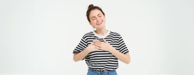 Gayri resmi giyinmiş güzel bir kadın resmi, kalp ve gülümseme, şükran ifade, beyaz arka plan üzerinde duran.